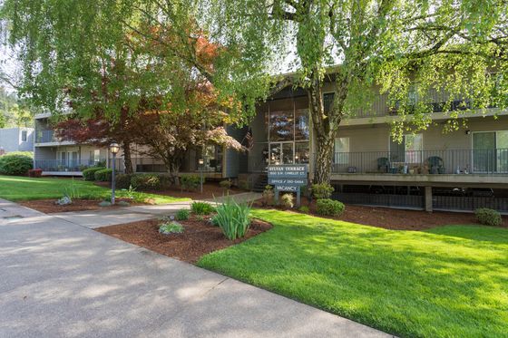 Charming apartment complex nestled amidst lush greenery, showcasing well-maintained landscaping and inviting patios in a serene setting.
