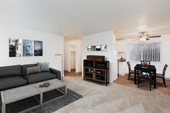 Contemporary open-plan living space featuring a stylish black sofa, modern dining area, and natural light from large windows.