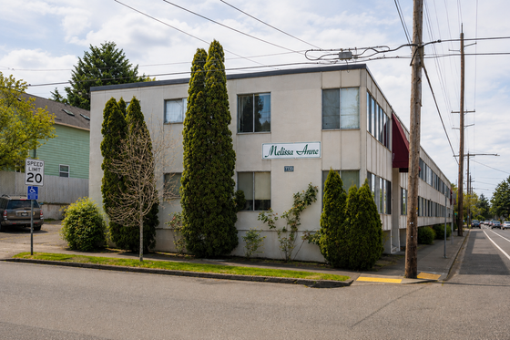 Charming apartment building with lush greenery and a welcoming facade, situated in a tranquil neighborhood.