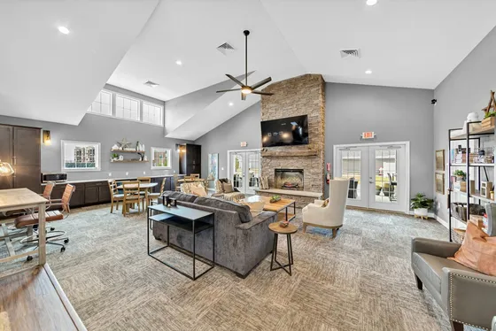 Inviting communal living room with modern furnishings, large stone fireplace, and abundant natural light, perfect for gatherings and relaxation.