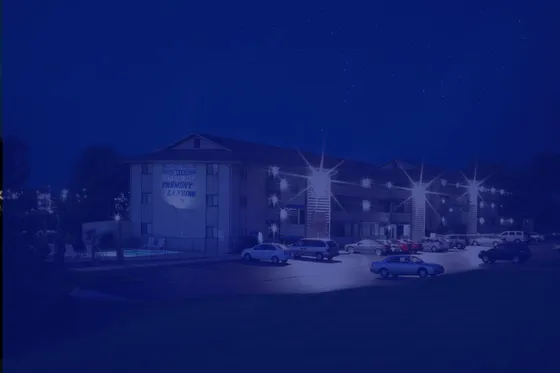 Exterior nighttime view of Fremont Landing Apartments with illuminated buildings, parking area, and residential community entrance.