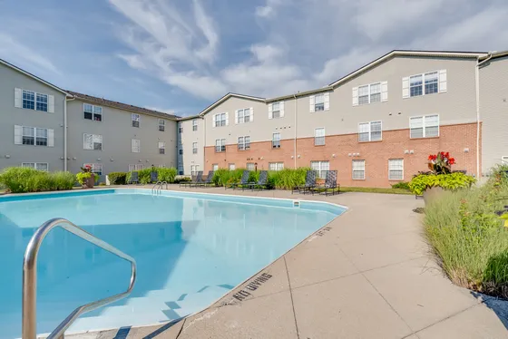 Inviting apartment complex with a sparkling outdoor pool, surrounded by lush greenery and modern architecture.