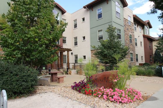 Beautiful apartment building with lush greenery and vibrant flowers.