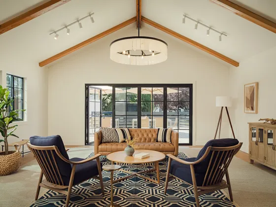 Elegant living room with vaulted ceiling, sleek chandelier, and stylish seating arrangement around a chic coffee table.