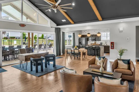 Spacious contemporary living area featuring elegant leather seating, a chic dining table, and a modern kitchen with stainless steel appliances. Sunlit interiors with large windows and patio access offer seamless indoor-outdoor living.