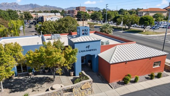 Charming leasing center at Casa Bandera, featuring vibrant architecture and lush landscaping, set against a backdrop of stunning mountain views.