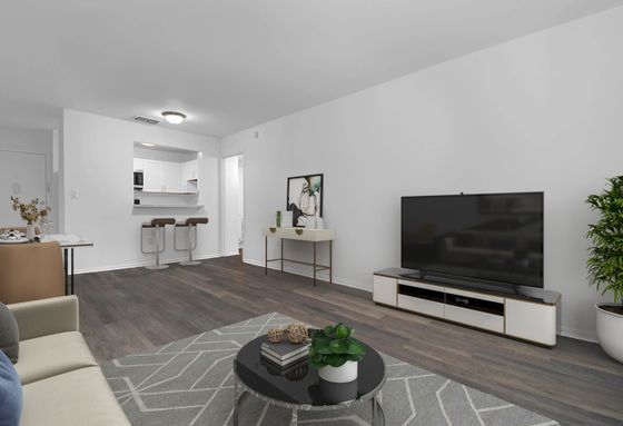 Modern open-plan living area with elegant hardwood floors, sleek TV unit, and cozy dining setup next to a stylish kitchen breakfast bar.