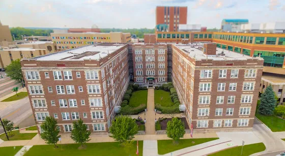Charming aerial view of a historic brick apartment complex with lush greenery in an urban setting.