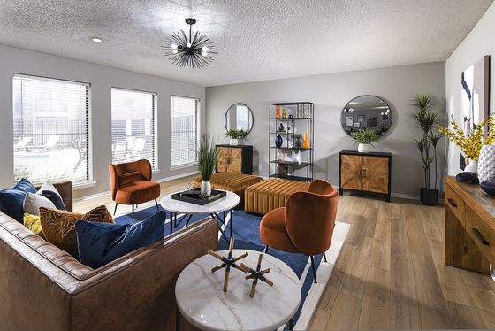 Modern and vibrant living room with stylish decor, large windows for natural light, and elegant furnishings including plush seating and a contemporary chandelier.