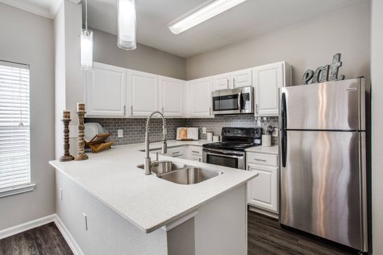 Modern kitchen with hardwood-floors, white quartz counter island, stainless steel appliances white cabinetry