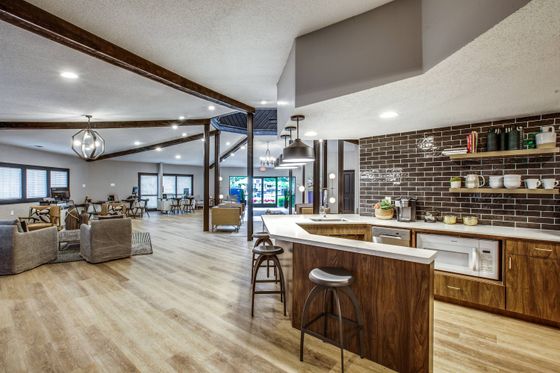 Leasing office with chairs and couch and community coffee bar, bar stools, wood flooring