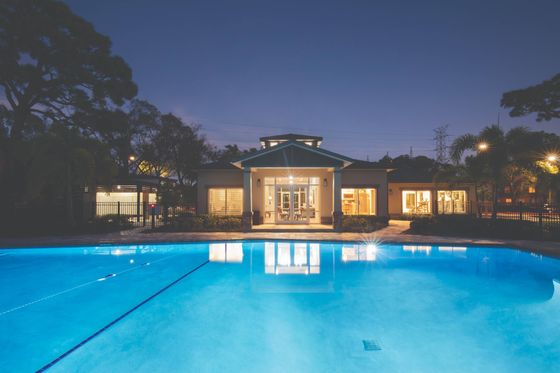 Brick leasing office overlooking a large, resort-style pool and trees