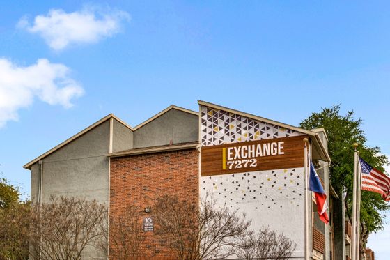 Angular brick exterior of apartment building with 'Exchange 7272' wooden plaque