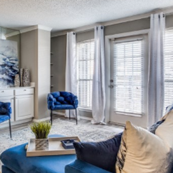 Living room with blue sectional, matching chair, large windows, patio door, and carpeted floor.