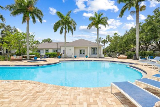 Luxury pool with sundeck and blue lounge chairs, next to leasing building