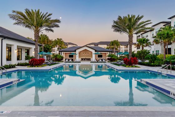 Brick leasing office overlooking a large, resort-style  and palm trees and native landscaping