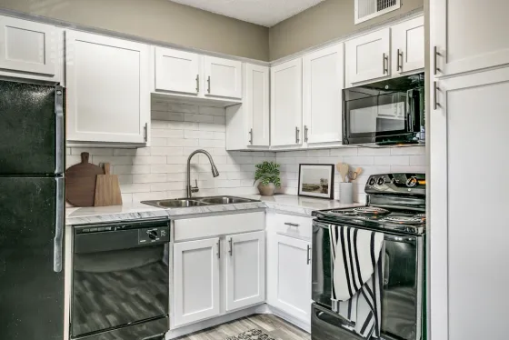 Modern kitchen with white cabinetry, black appliances, gooseneck faucet, and timeless subway backsplash