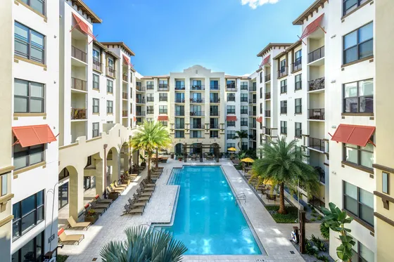 View of pool with lounge seating and apartment building