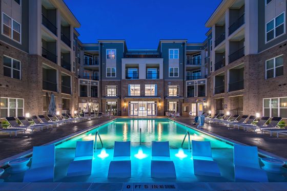 Night view of pool and apartments with lounge chairs in the water