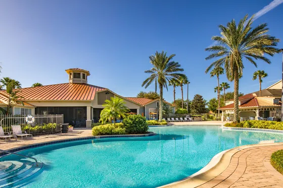 Clubhouse view by pool with palm trees and lounge seating