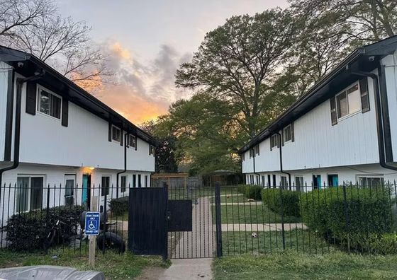 Charming modern apartment complex with lush greenery and inviting walkway at sunset.