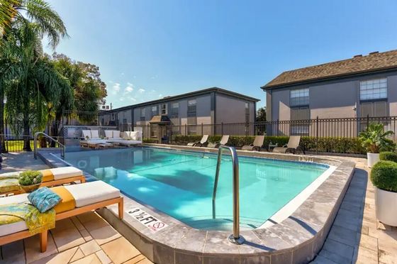 Inviting swimming pool area with stylish lounge chairs and lush greenery, perfect for relaxation on a sunny day.