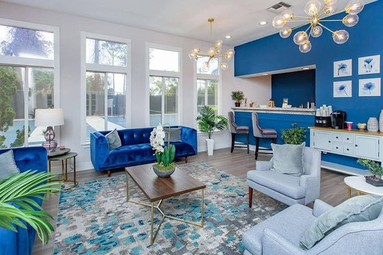 Chic and contemporary living room with plush blue sofas, modern lighting, and a stylish bar area.