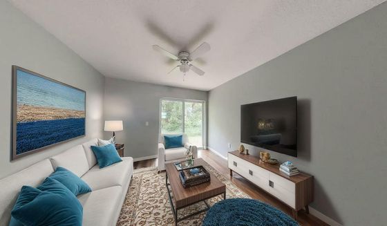 Cozy living room with modern decor, featuring a comfortable sofa with blue cushions, flat-screen TV, and large window illuminating the space.