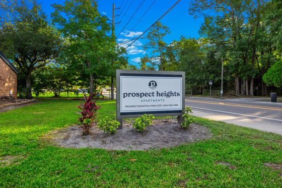 Inviting entrance to Prospect Heights Apartments, surrounded by lush greenery and a peaceful neighborhood setting.