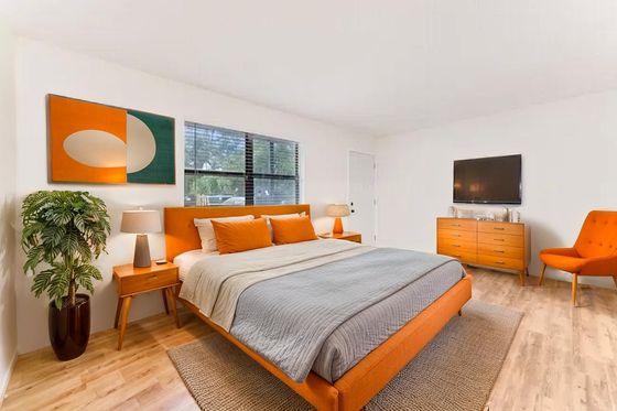 Inviting bedroom with modern orange furniture, plush bed, and stylish decor, creating a warm and cozy ambiance.