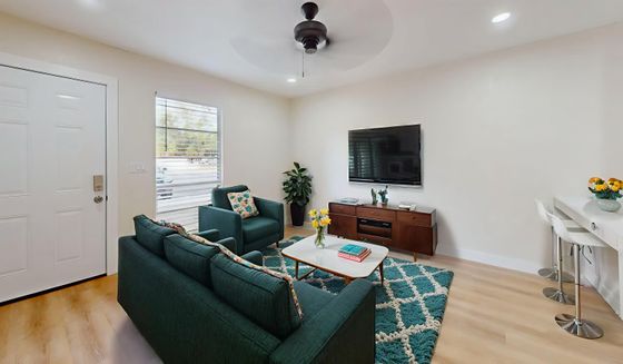 Inviting living room with stylish teal sofas, elegant decor, and a modern TV setup, perfect for relaxation and entertainment.