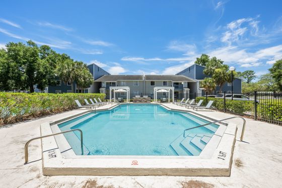 Inviting apartment pool area with lush surroundings and modern poolside seating, perfect for relaxation.