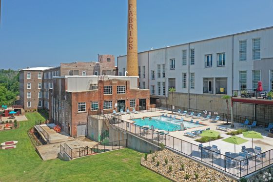 Charming historic building conversion with a modern outdoor pool area, surrounded by lush greenery and stylish patio seating.