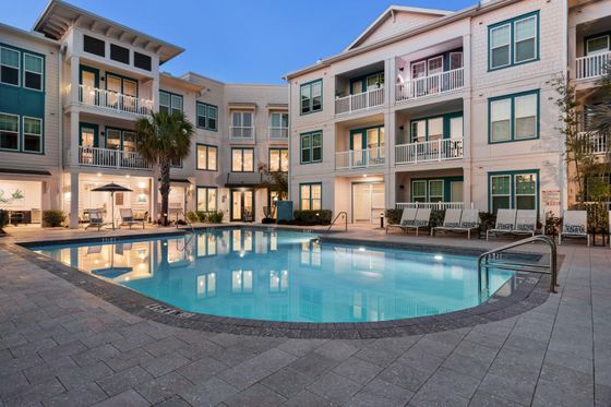 Elegant apartment complex with illuminated pool and serene ambiance.