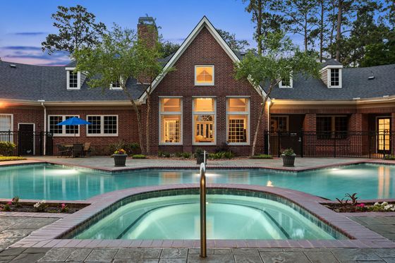 Charming brick house with elegant arched windows and inviting outdoor pool area, perfect for serene evenings and social gatherings.