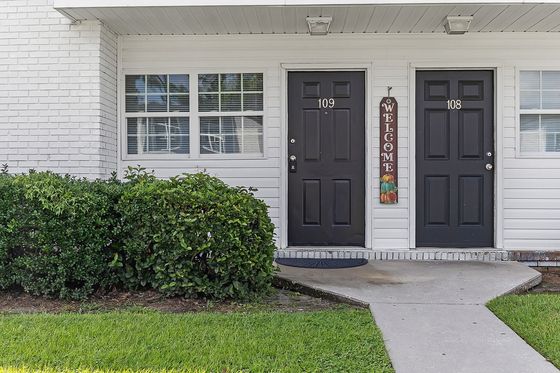 Inviting apartment entrance with charming black doors, surrounded by well-maintained greenery and a welcoming atmosphere.