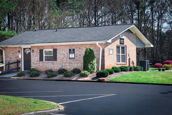 Charming brick leasing office surrounded by lush greenery and vibrant landscaping.