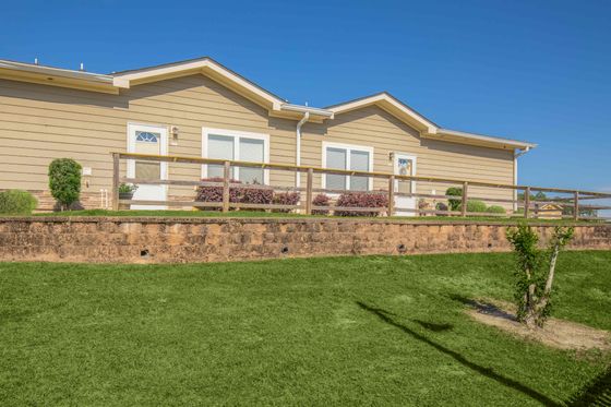 Charming duplex apartment with modern exterior, surrounded by lush green lawn and pristine landscaping.