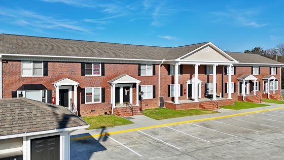 Charming red-brick townhouse complex with elegant white columned entrances, offering ample parking and modern living.