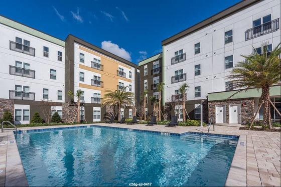 Inviting apartment complex featuring modern architecture with a stunning outdoor pool and lush palm landscaping.