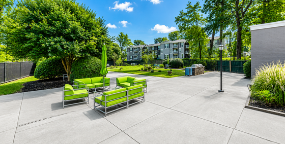 Chic modern outdoor space with vibrant green seating and lush gardens in a stylish apartment complex.