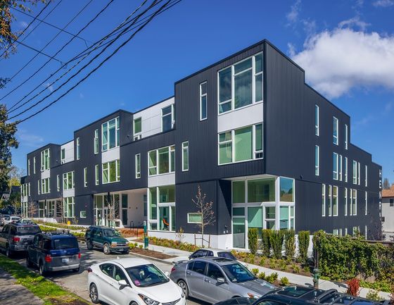 Contemporary black and white apartment complex with large windows, showcasing modern urban living in a vibrant neighborhood.