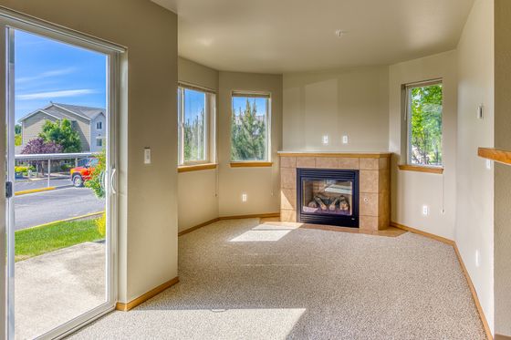 Bright living room with large windows, cozy fireplace, and sliding door leading to a sunny outdoor space.