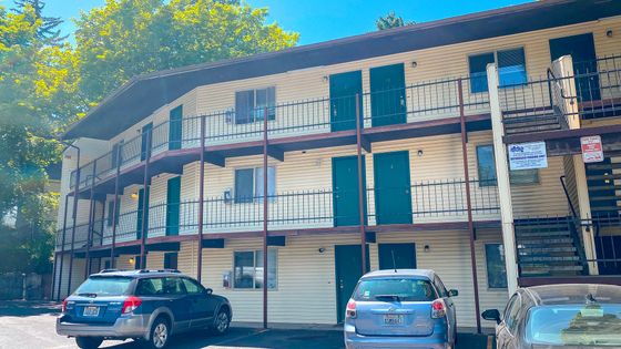 Charming multi-level apartment complex with balconies, modern design, and convenient outdoor parking in a lush, green setting.