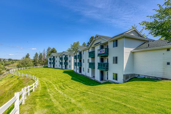 Charming apartment complex featuring vibrant balconies, lush green lawns, and scenic views in a serene environment.