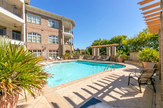 Inviting outdoor pool area with elegant stone architecture, surrounded by lush greenery and comfortable lounge chairs.