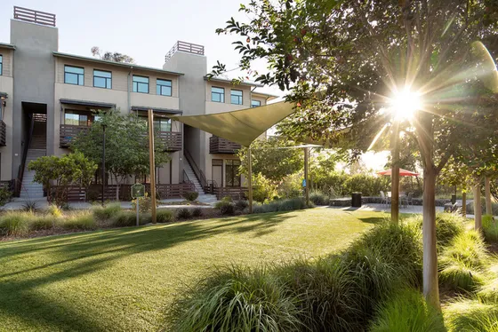 Charming residential building with lush green gardens and modern architecture basking in the warm sunlight.