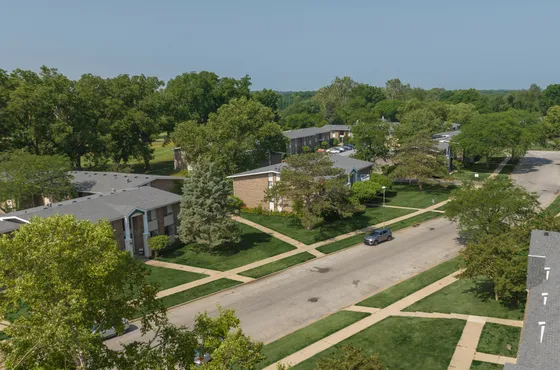 Charming suburban neighborhood with lush greenery, spacious apartment buildings, and peaceful streets.