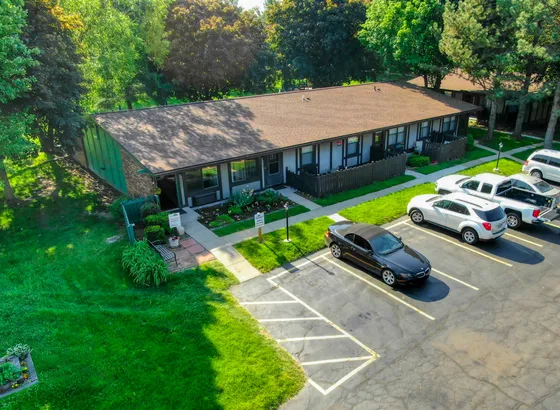Inviting residential building with lush green surroundings, featuring well-maintained gardens and ample parking space.