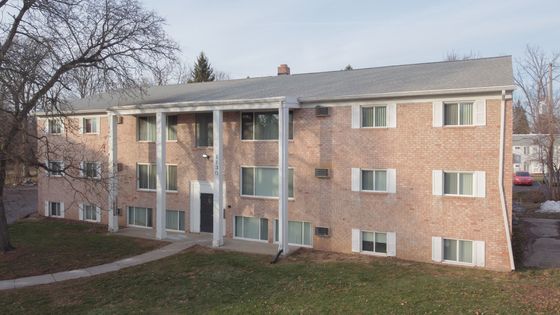 Charming brick apartment building with large windows, nestled in a serene neighborhood, ideal for comfortable living.